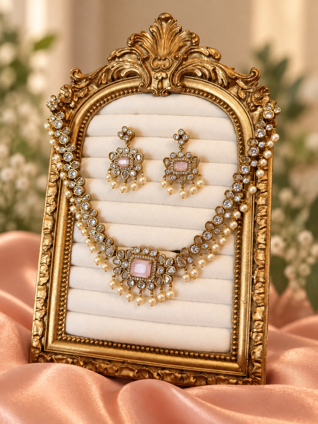 Roshan blush-pink necklace and matching earrings displayed in an ornate gold frame